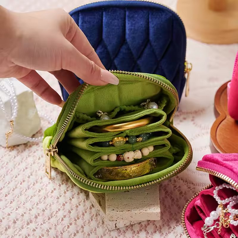 Portable travel jewelry bag with soft velvet lining, zipper closure, and multiple pockets for protecting and organizing jewelry.